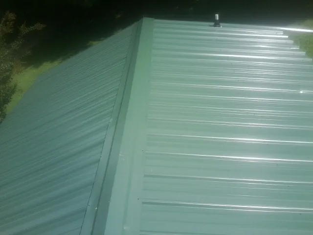 New green metal panels meeting at the ridge of a roof — Flat Roof Repair work by our crew in Wise River