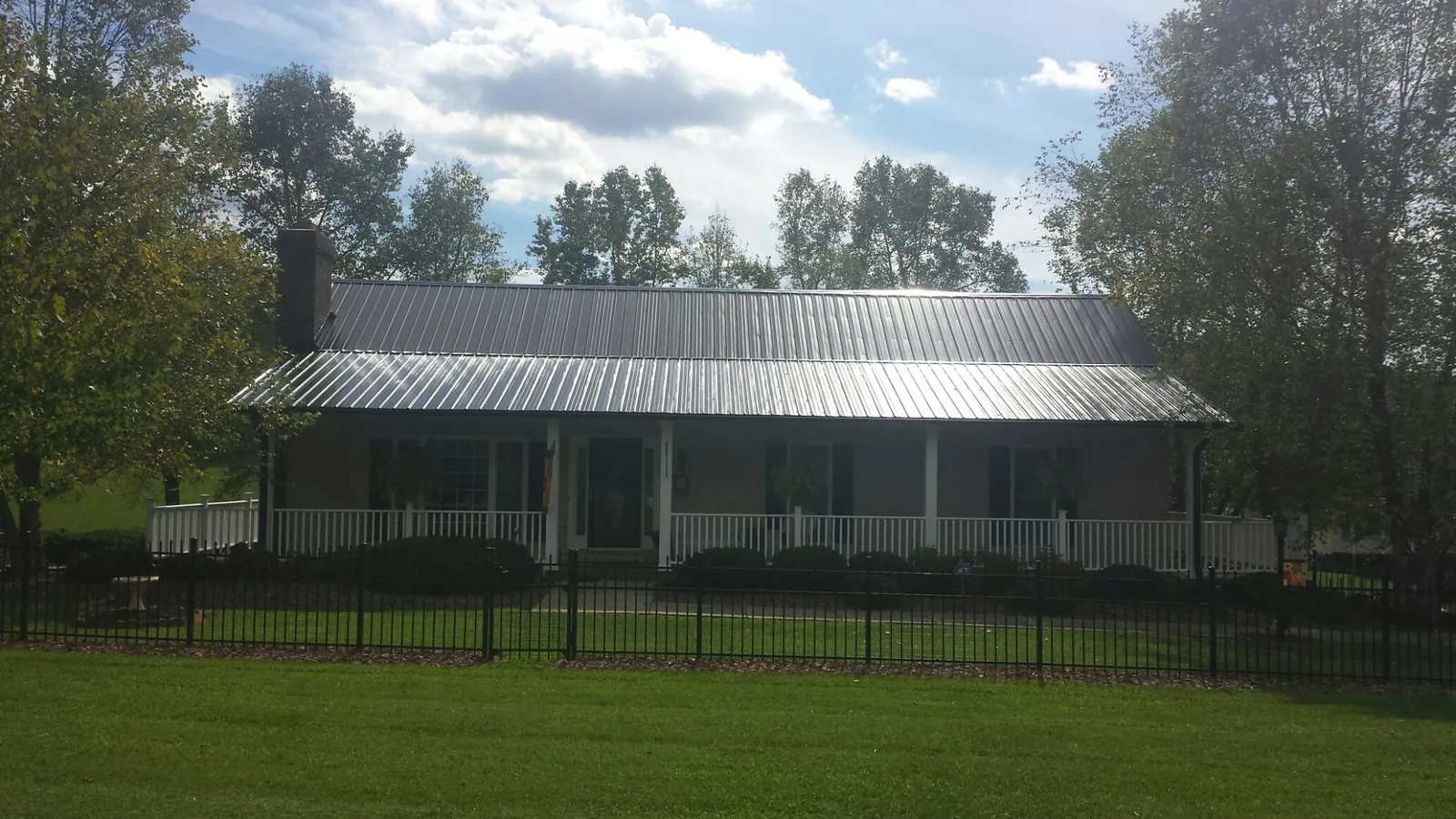 Gray metal roof on a brick ranch with a full width front porch — Gutter Guard Installation work by our crew in Wise River
