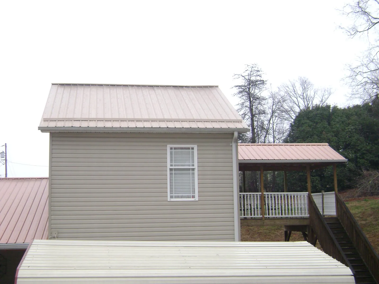 Tan metal roofs on a two story addition and attached porch, from a Roof Replacement job in Wise River