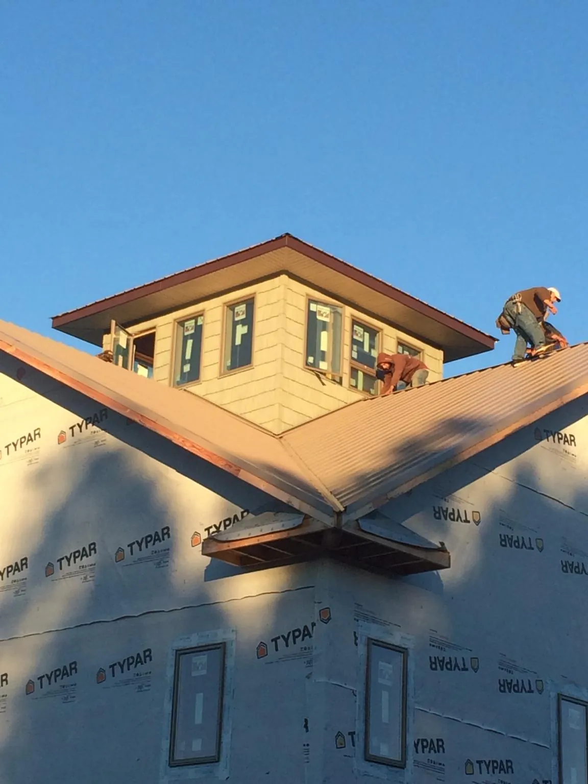 Roofers working around a rooftop cupola on a new metal roof at sunset — Roof Waterproofing in Wise River by Roofing Brothers